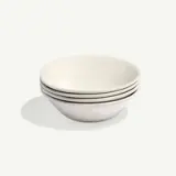 A stack of four white ceramic bowls on a light background.