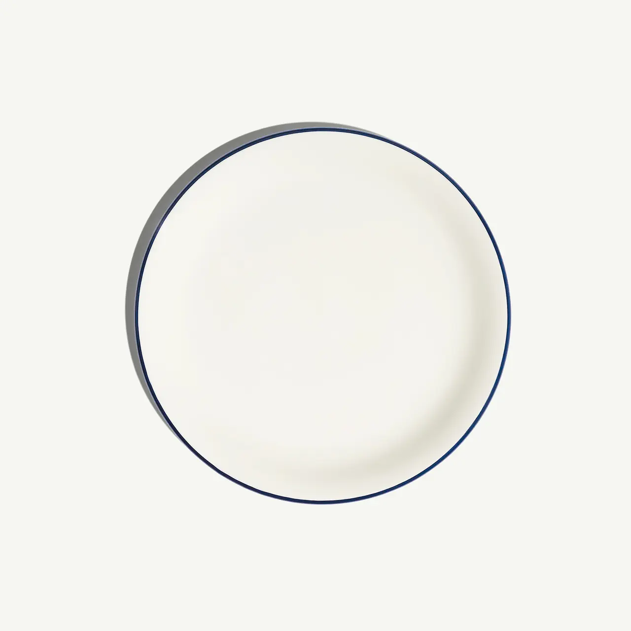A blank white plate with a blue rim is centered on a light background.