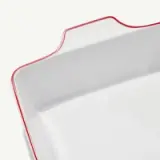 A close-up of a white square ceramic dish with a red rim and the word "modern" embossed on one side.