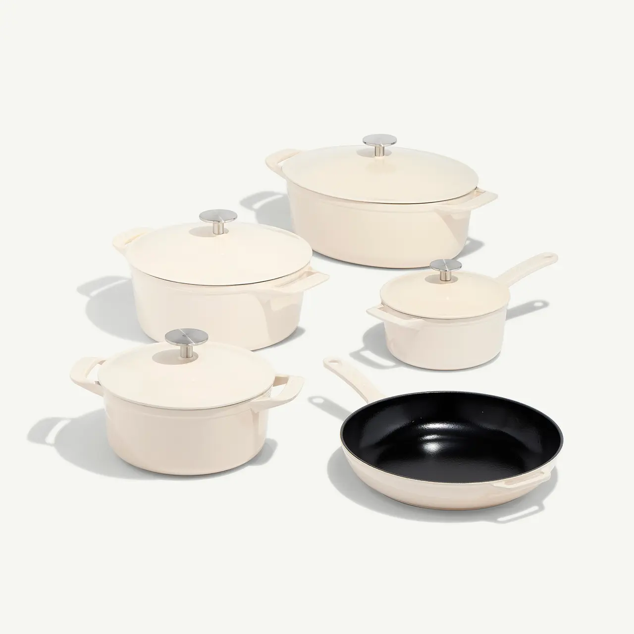 A set of elegant white cookware with a single black skillet, each piece featuring matching lids and handles, displayed on a light background.