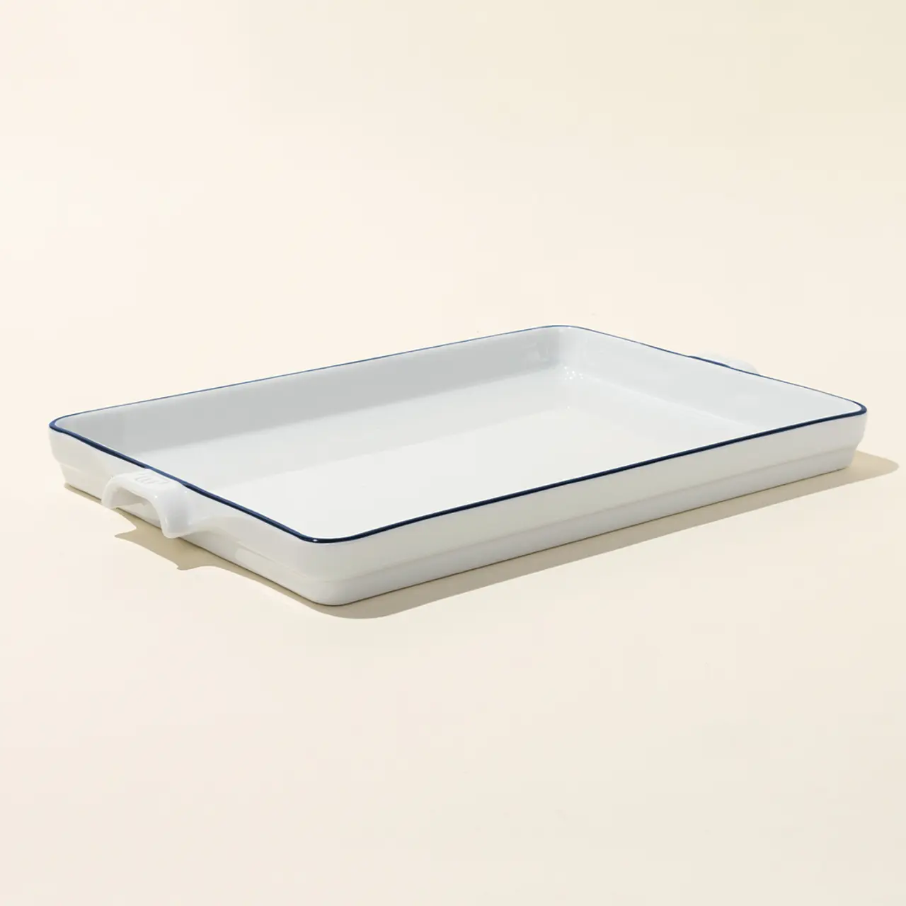 A white ceramic baking dish with blue trim sits on a neutral background.
