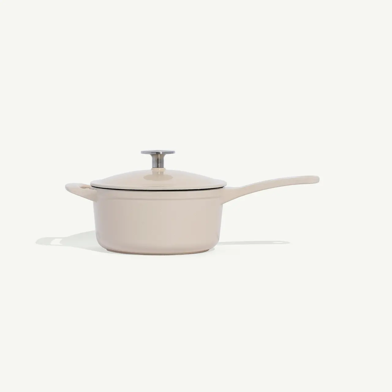 A beige saucepan with a lid is centered against a white background.