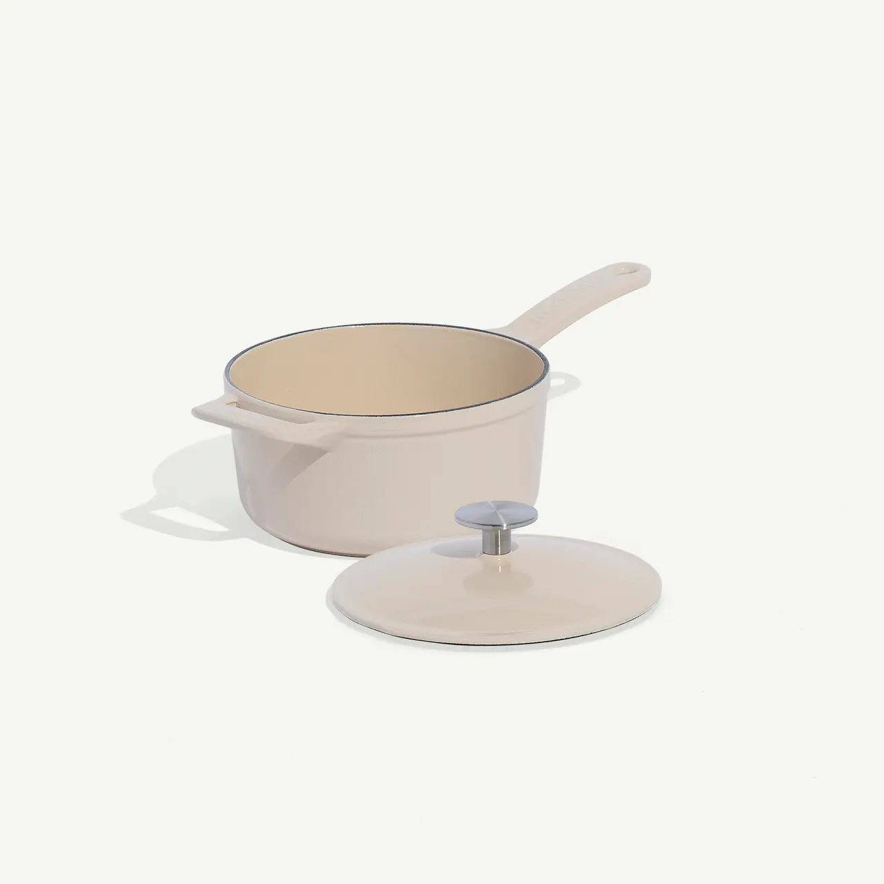 A beige saucepan with a matching lid is set against a plain background.
