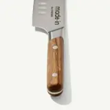 A close-up view of a chef's knife with a wooden handle, displaying the brand "Made In" etched on the blade.