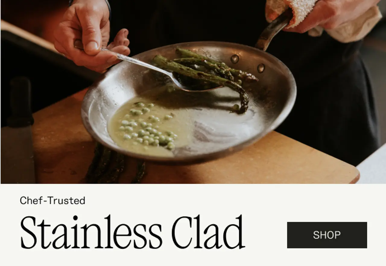 A chef skillfully stirs asparagus and green peas in a stainless steel pan, highlighting the quality of chef-trusted cookware.