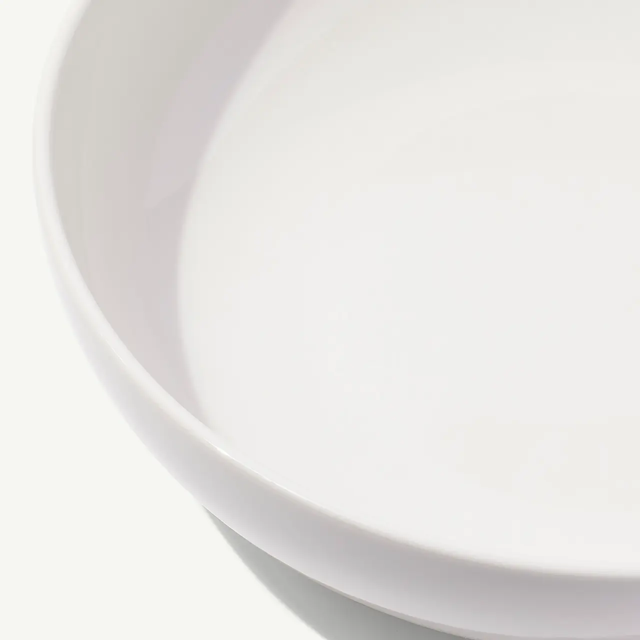 A close-up view of a simple, empty white bowl against a white background.