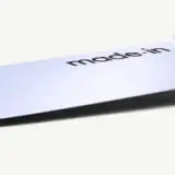 A close-up of a sleek metallic surface with "made in" printed in black font.