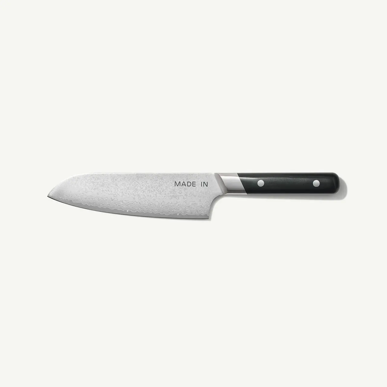 A chef's knife with a black handle and a steel blade lies on a white background.