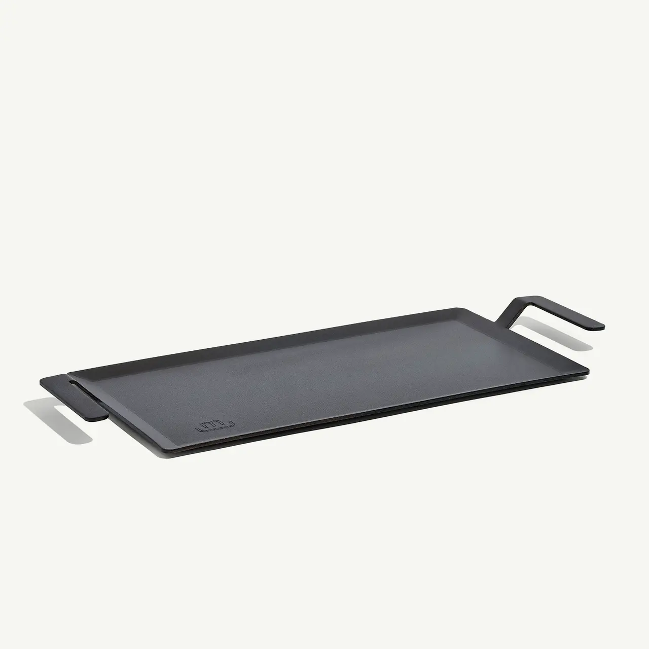 A black rectangular cast iron griddle with a pair of integrated handles sits against a light background.