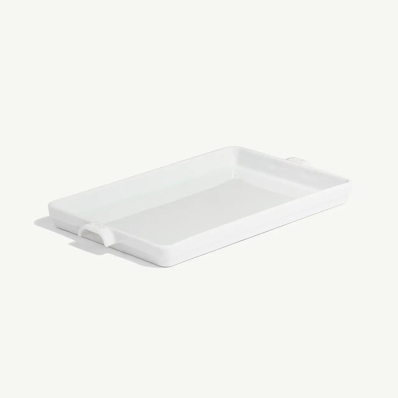 A white rectangular ceramic dish with handles is displayed on a plain background.