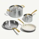 Four cooking pots and pans in varying sizes, featuring a sleek silver finish and gold-colored handles.