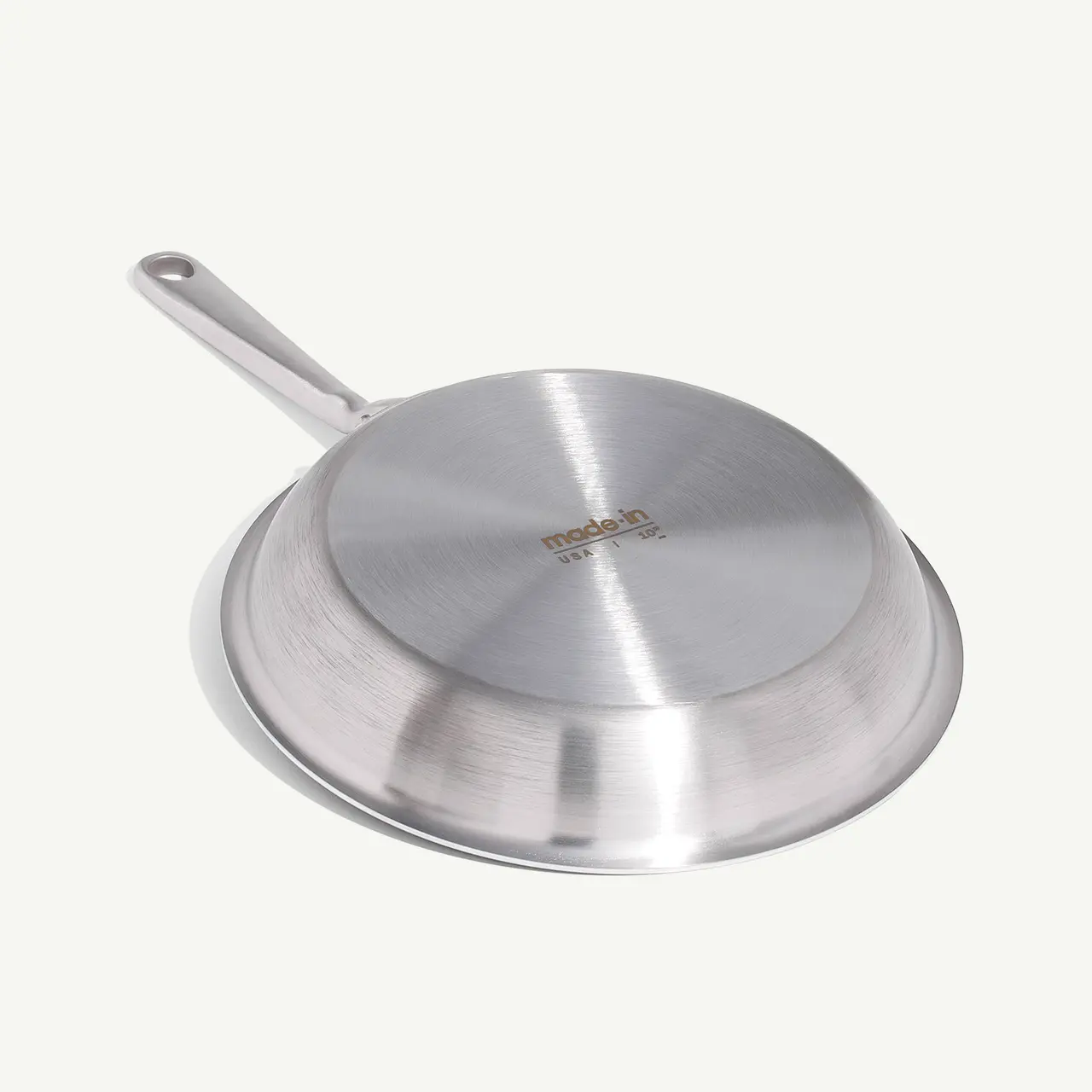 A stainless steel frying pan with a long handle is shown against a light background.