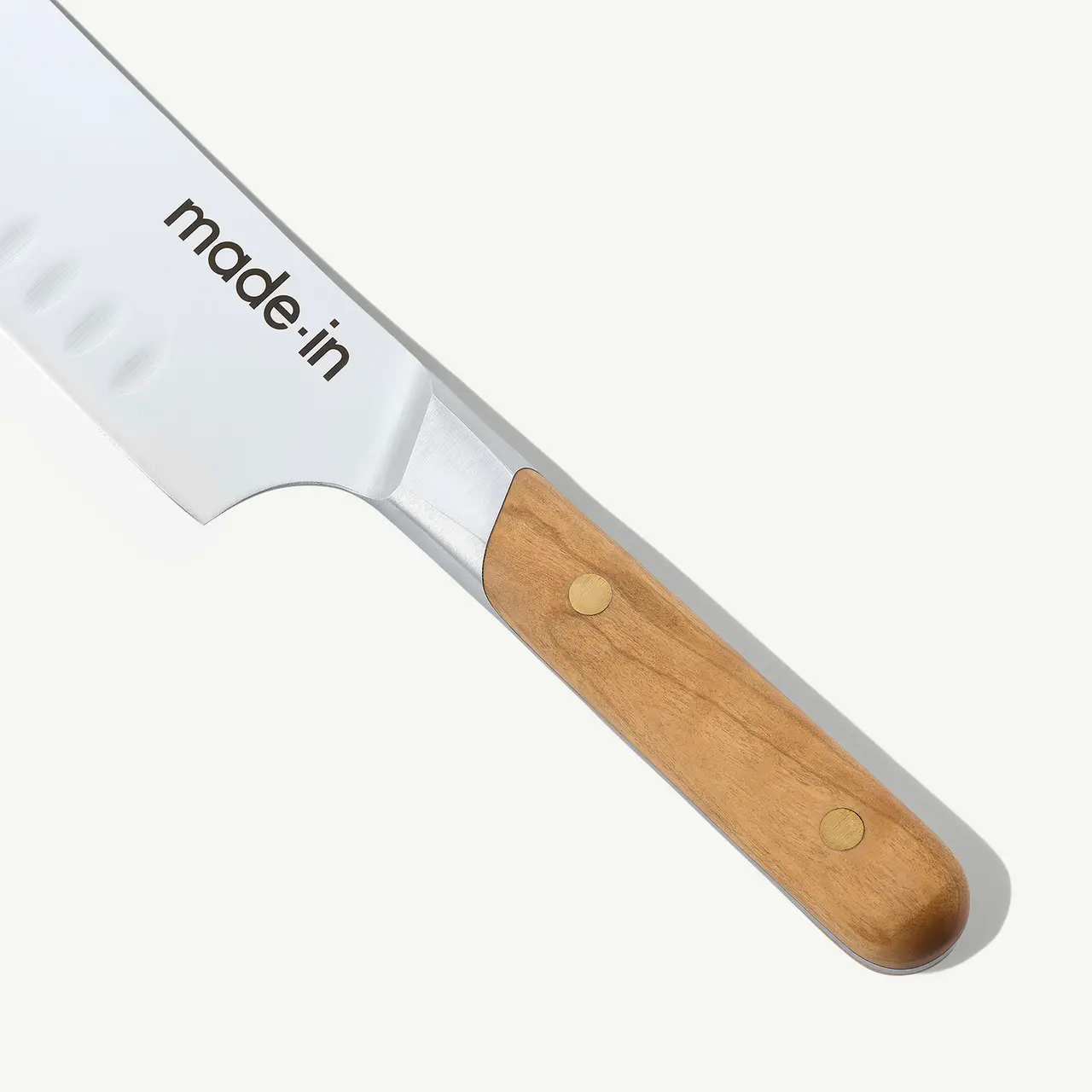 A close-up of a kitchen knife with a wooden handle and the text "made.in" imprinted on its blade.