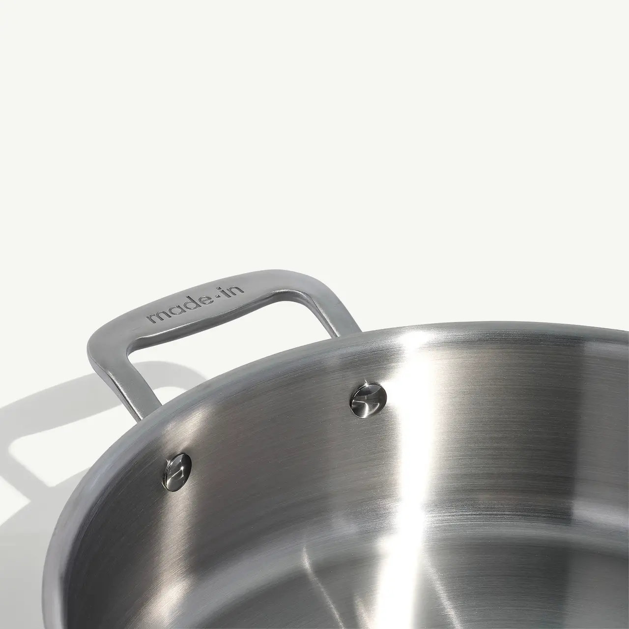 A close-up view of a stainless steel pot with a "made in" engraving on its handle, highlighting its sturdy design and material.
