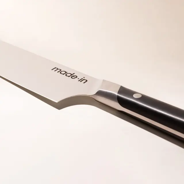 A close-up of a chef's knife with the words "made in" on the blade, signaling the brand or origin of the knife.