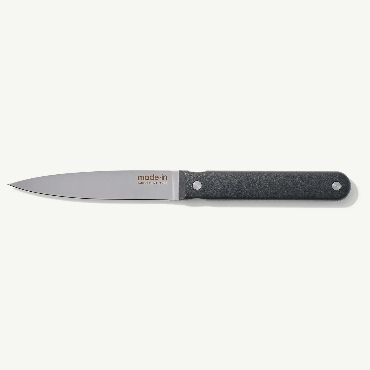 A chef's knife with a black handle and the brand "made in" imprinted on the blade is lying on a white background.