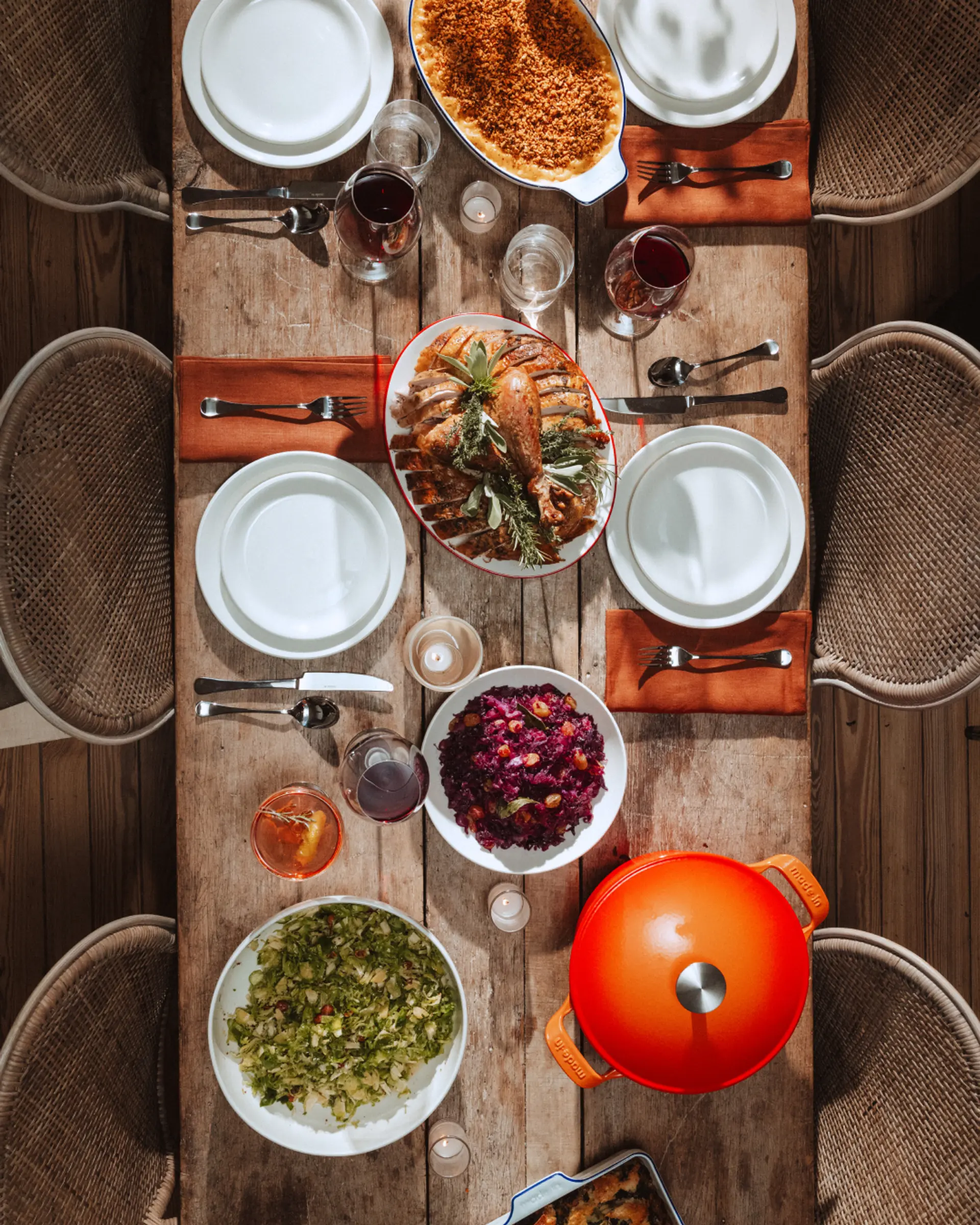 A rustic table setting featuring a variety of dishes including salad, bread, and beverages, viewed from above.