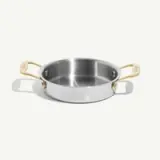 A stainless steel cooking pot with gold-colored handles sits on a neutral background.
