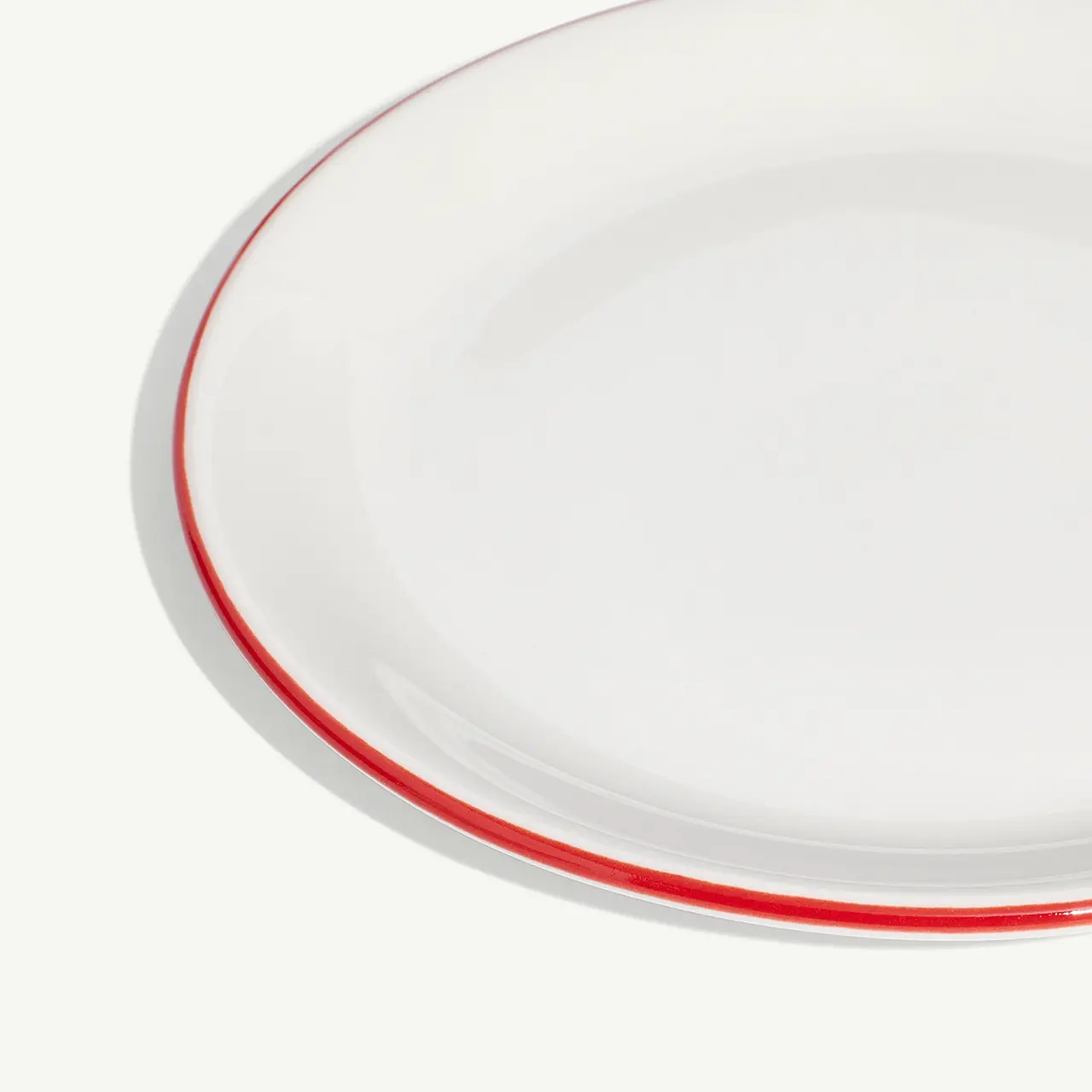 A close-up of a white circular plate with a thin red border against a light background.