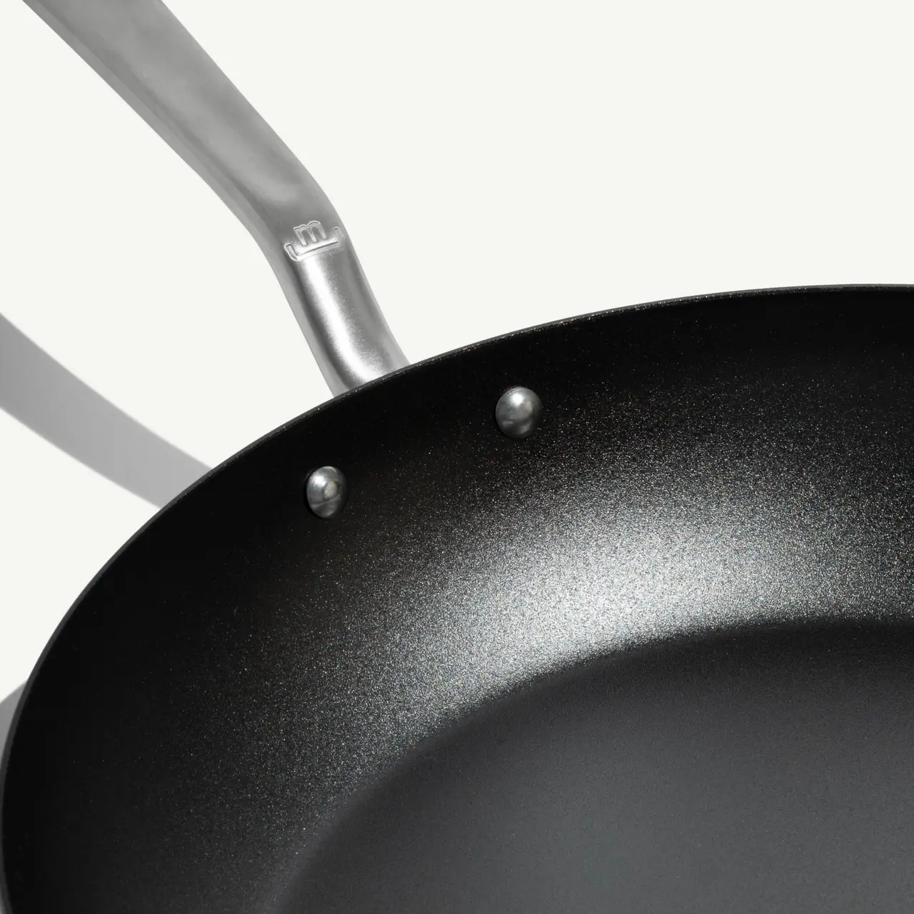 A close-up view of a non-stick frying pan with a stainless steel handle.