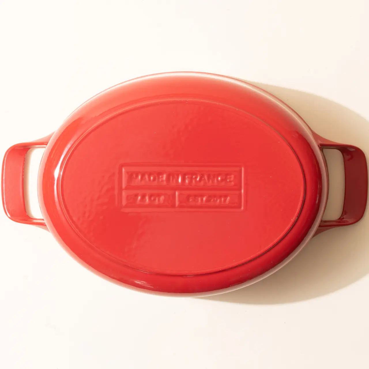 A red oval casserole dish with side handles and a lid, displaying "MADE IN FRANCE" embossed text.