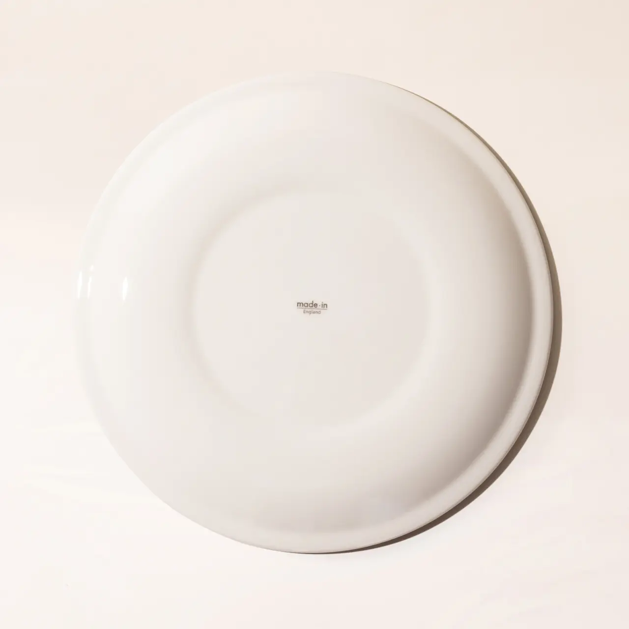 A plain white plate with a small "made in" text at the center on a light background.