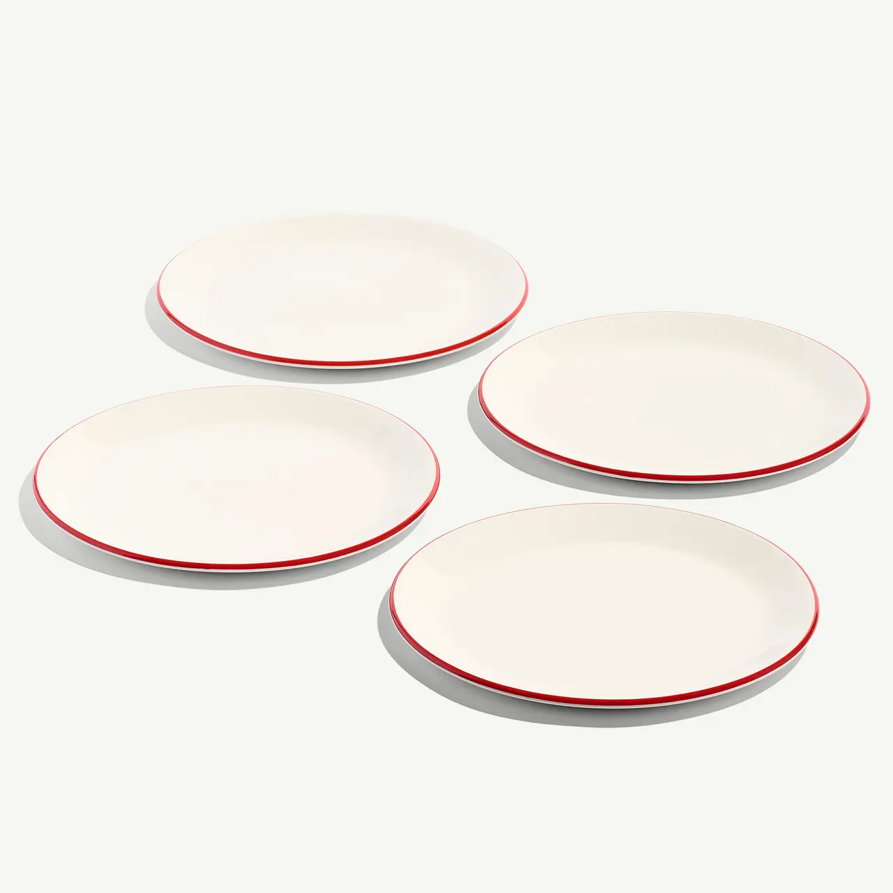 Four empty white plates with red trim are arranged on a light background.