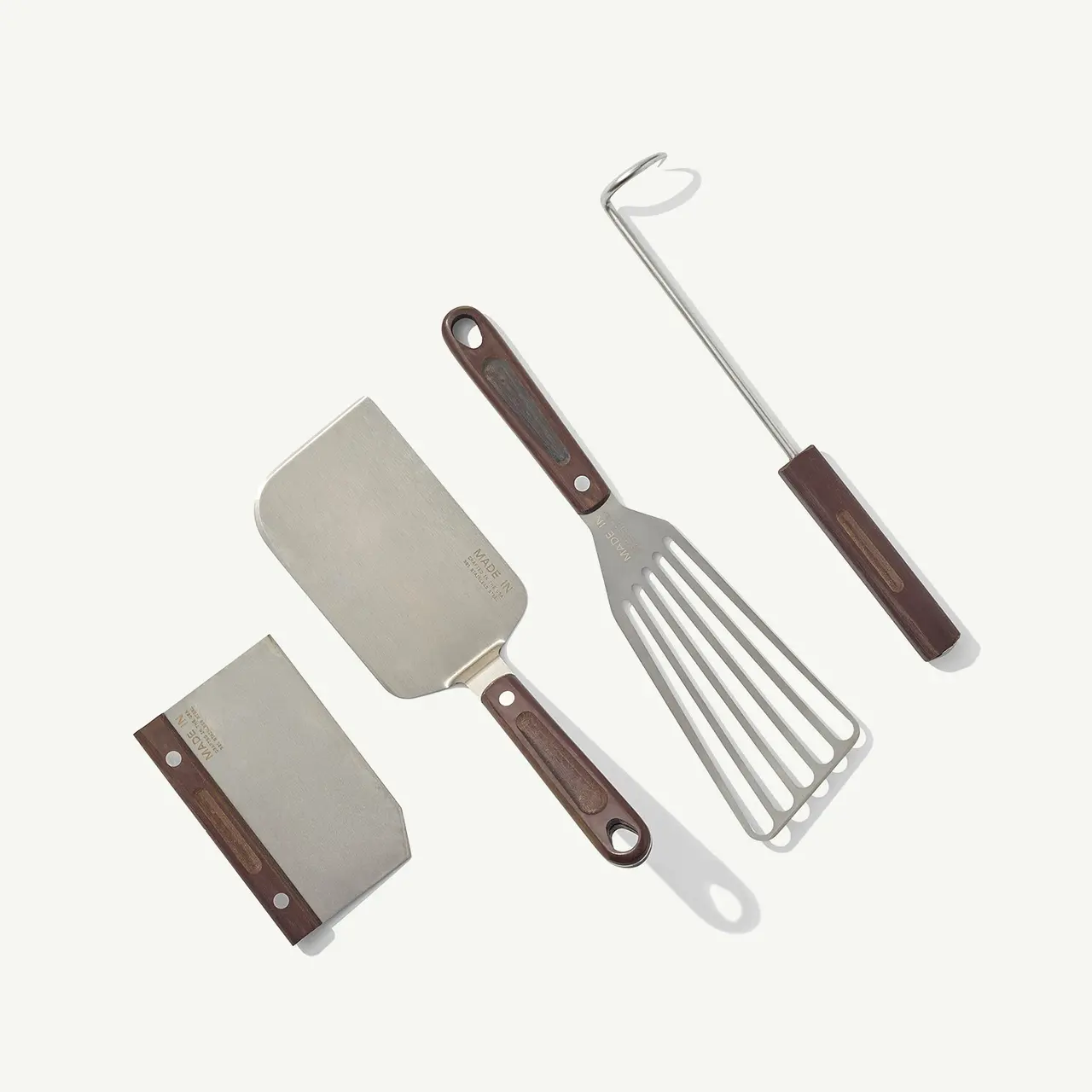 Vintage kitchen utensils, including two spatulas and a fork, with wooden handles on a plain background.