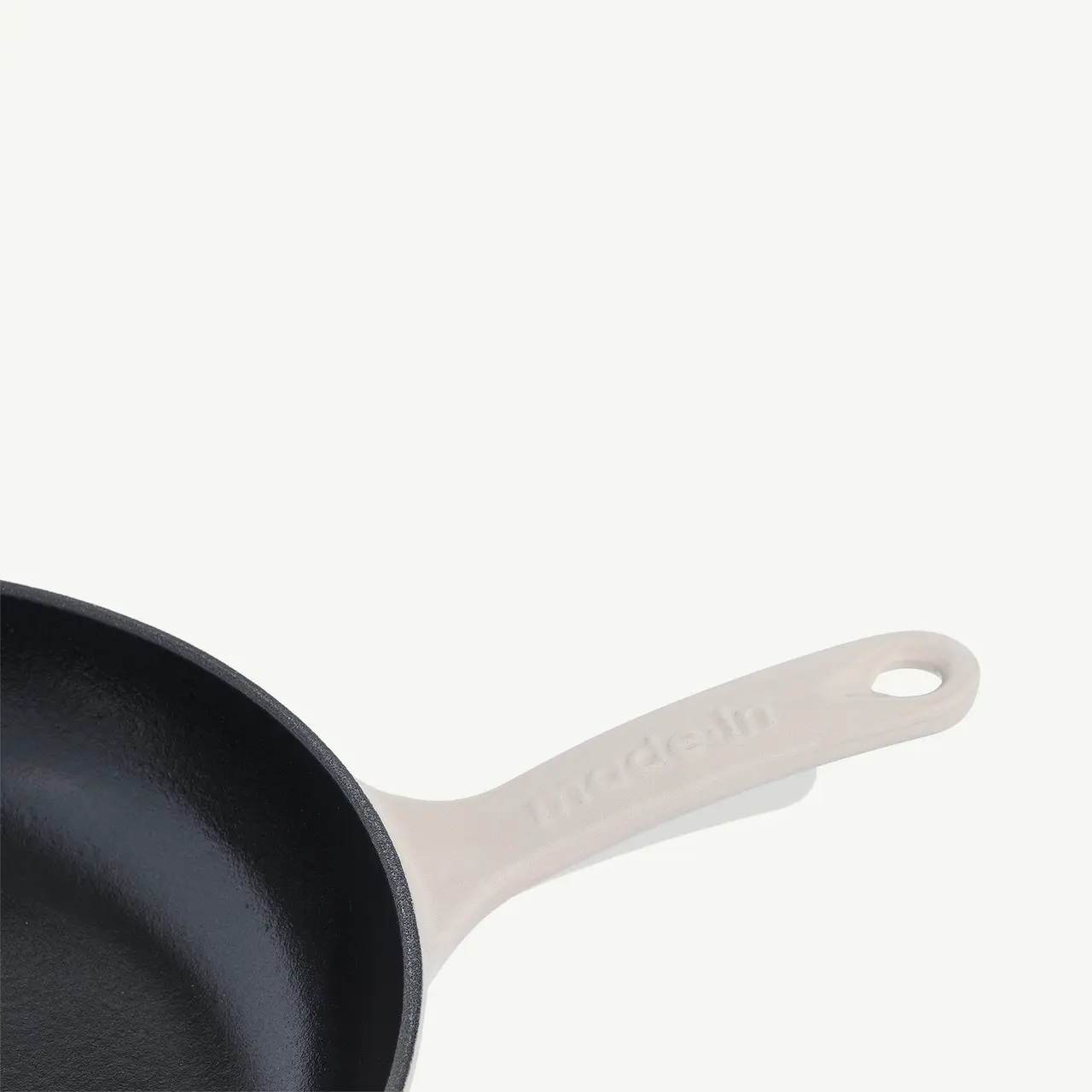 A black cast iron skillet with a light-colored handle positioned diagonally against a white background.