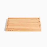 A rectangular bamboo cutting board with a juice groove on the perimeter and the words "MADE IN" inscribed on one side.
