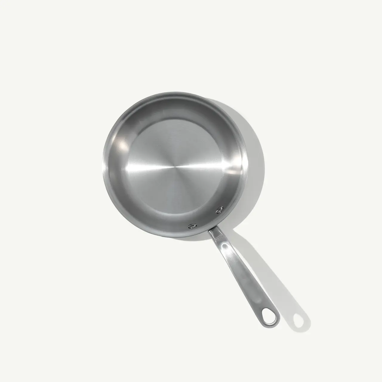 A stainless steel frying pan with a long handle is displayed against a light grey background.