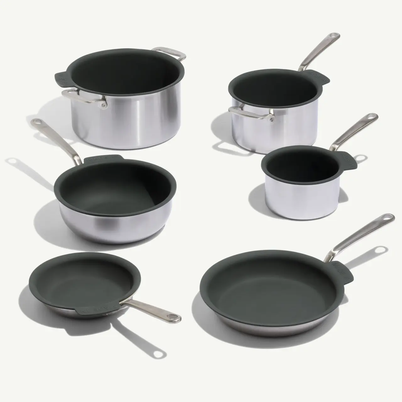 A collection of stainless steel pots and pans with dark green non-stick interiors.