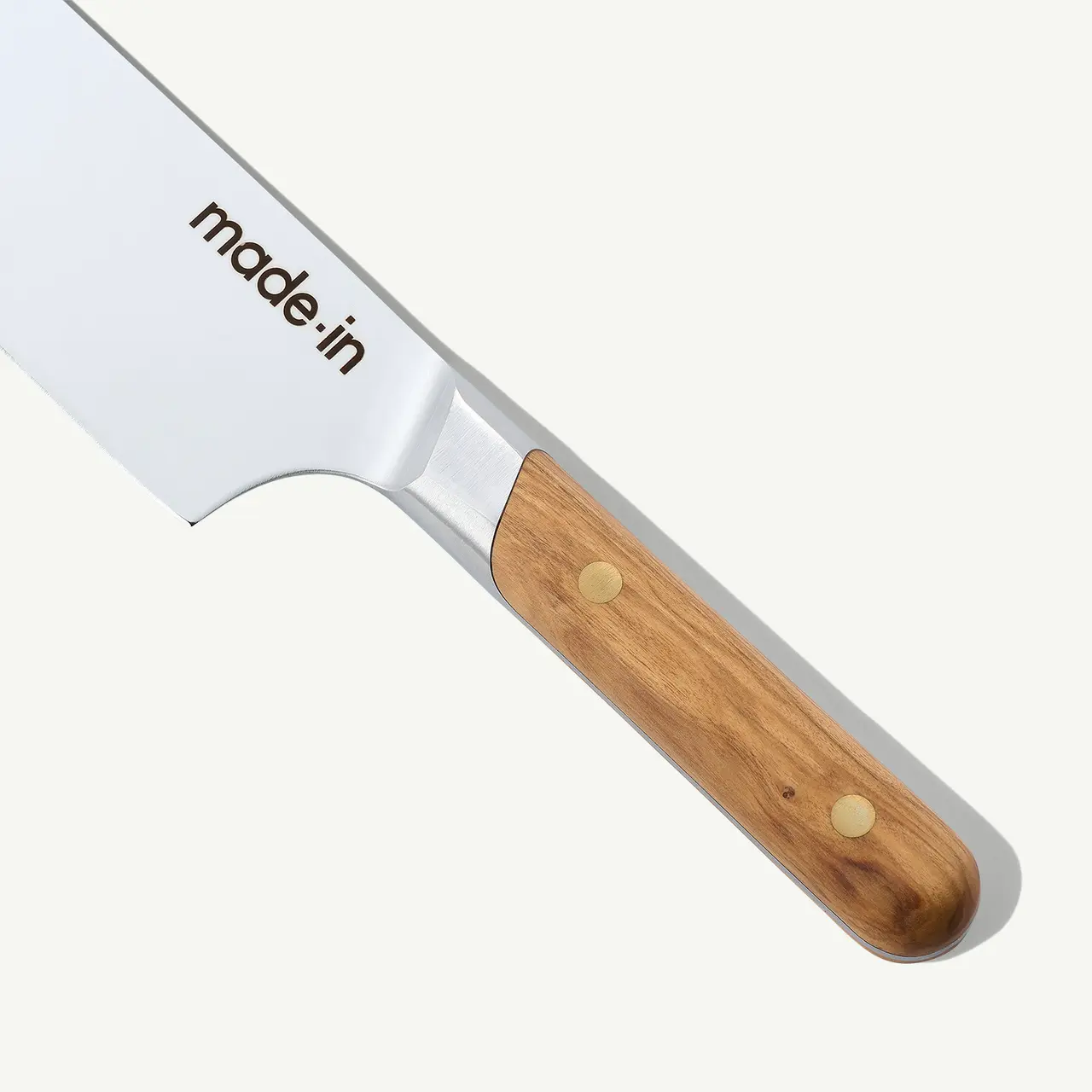 A close-up of a kitchen knife with a wooden handle and the words "made in" on the blade against a white background.