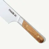 A close-up of a kitchen knife with a wooden handle and the words "made in" on the blade against a white background.