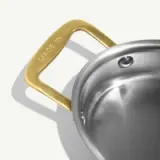 A stainless steel pot with a brass handle engraved with "MADE IN."
