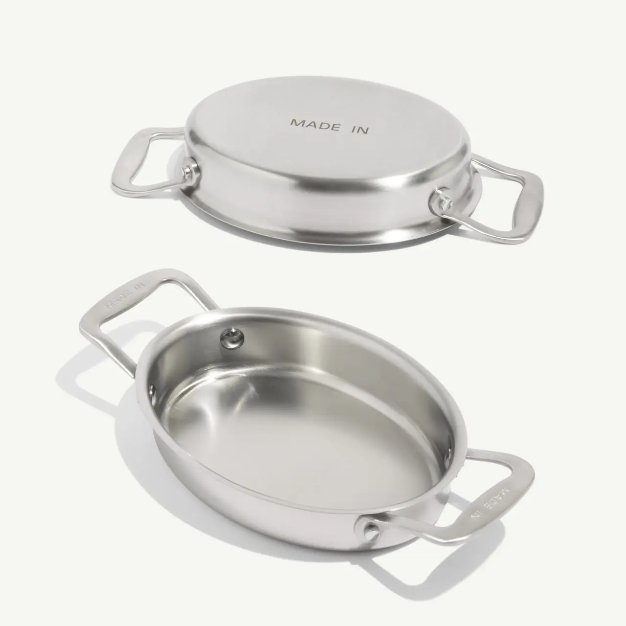 A sleek, stainless steel cookware piece with two handles, featuring a flat lid and an oval base.