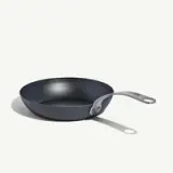 A black non-stick frying pan with a silver handle is pictured against a light background.