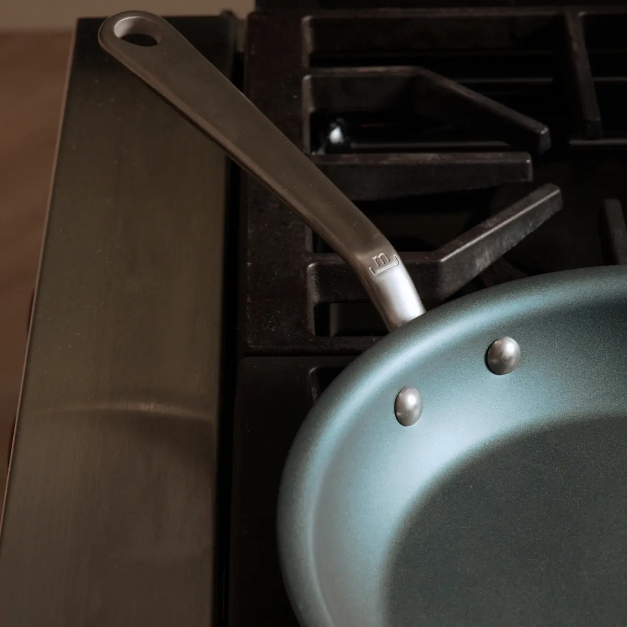 A non-stick frying pan with a metal handle sits on a gas stove top.