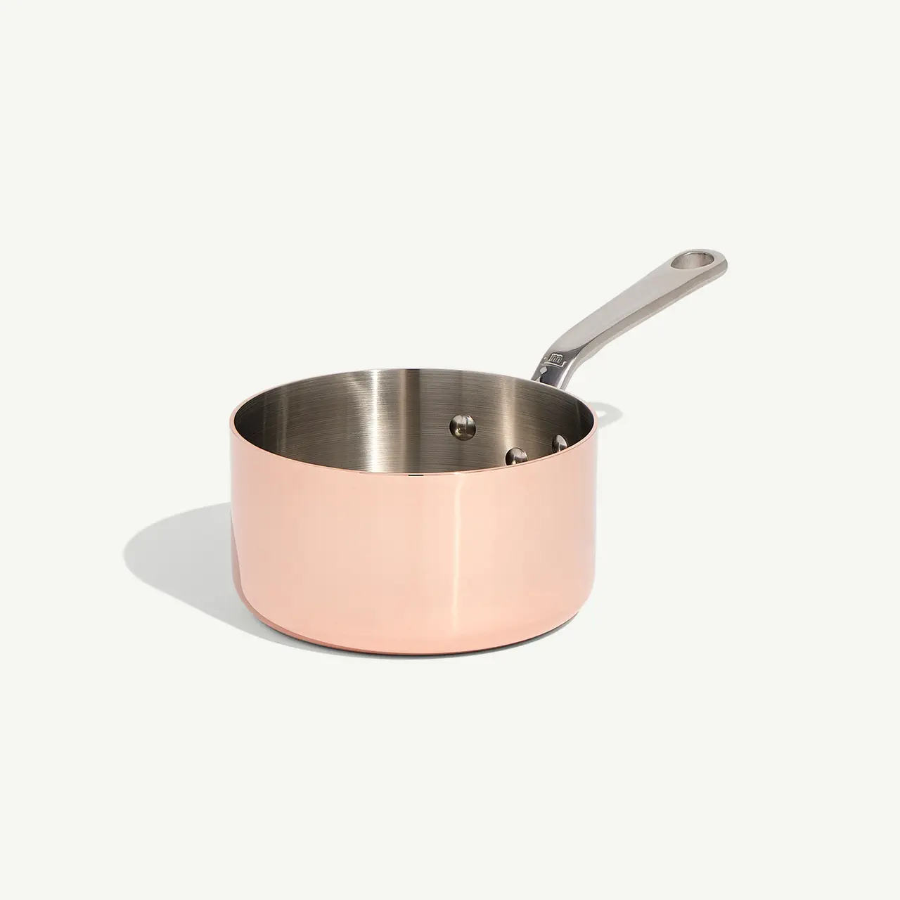A pink-colored stainless steel saucepan with a long handle set against a light background.