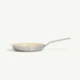 A stainless steel frying pan with a long handle is isolated against a white background.