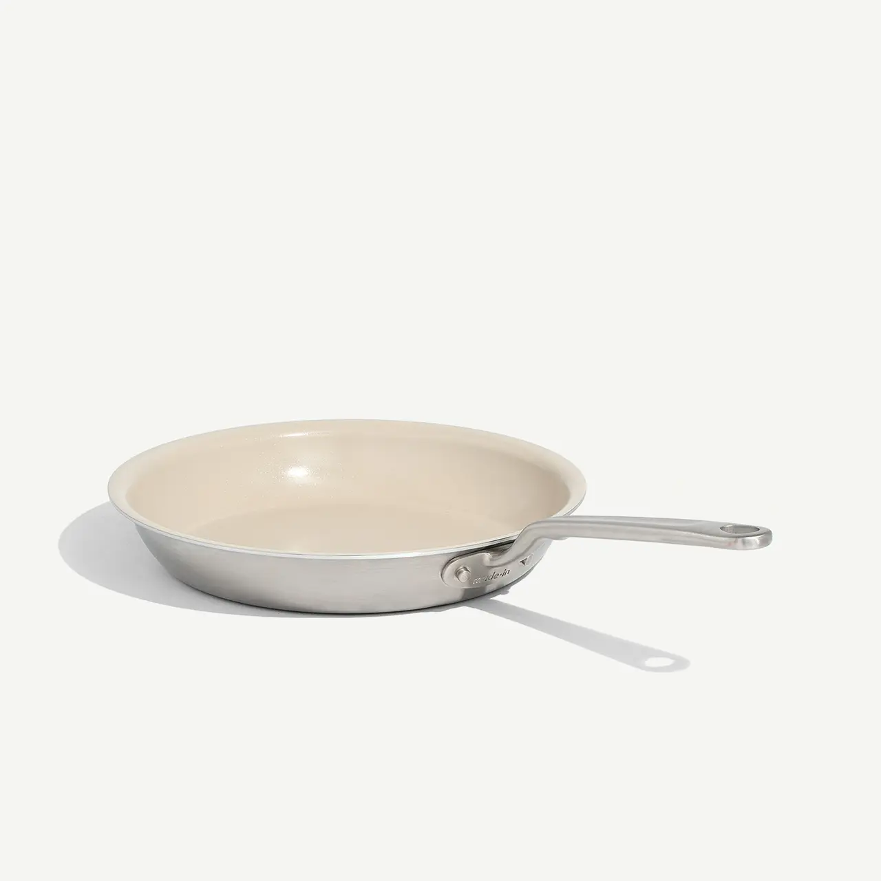 A non-stick frying pan with a stainless steel handle is positioned on a plain background, casting a soft shadow to one side.