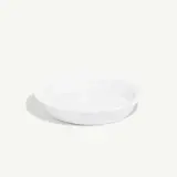 A simple white shallow bowl is centered on a plain background.
