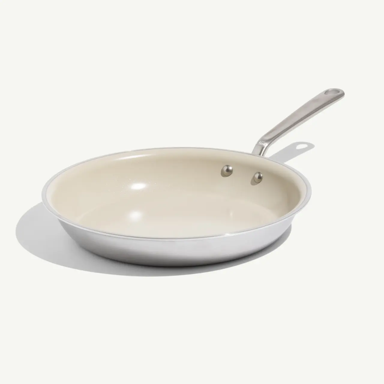 A shallow, round frying pan with a shiny stainless steel exterior and a light-colored non-stick interior.