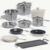 A collection of various cooking pots and pans, including stainless steel, non-stick, and enameled cookware, arranged in an appealing layout.