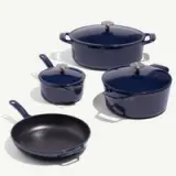 A set of navy blue cookware, including pots with lids and a frying pan, is arranged on a light background.