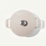 A light-colored Dutch oven with a metallic lid featuring a stylized "OU" logo is displayed from above.