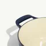 A close-up view of a saucepan with a dark handle on a light background, showcasing the handle detail.