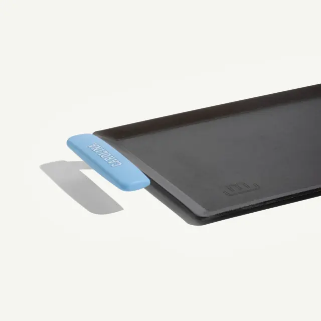 A black griddle with a blue silicone handle for easy gripping and maneuvering.