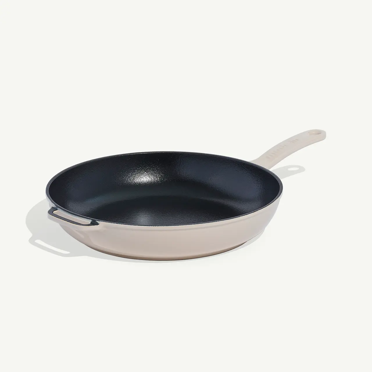 A non-stick frying pan with a beige exterior and a long handle rests on a plain white surface.