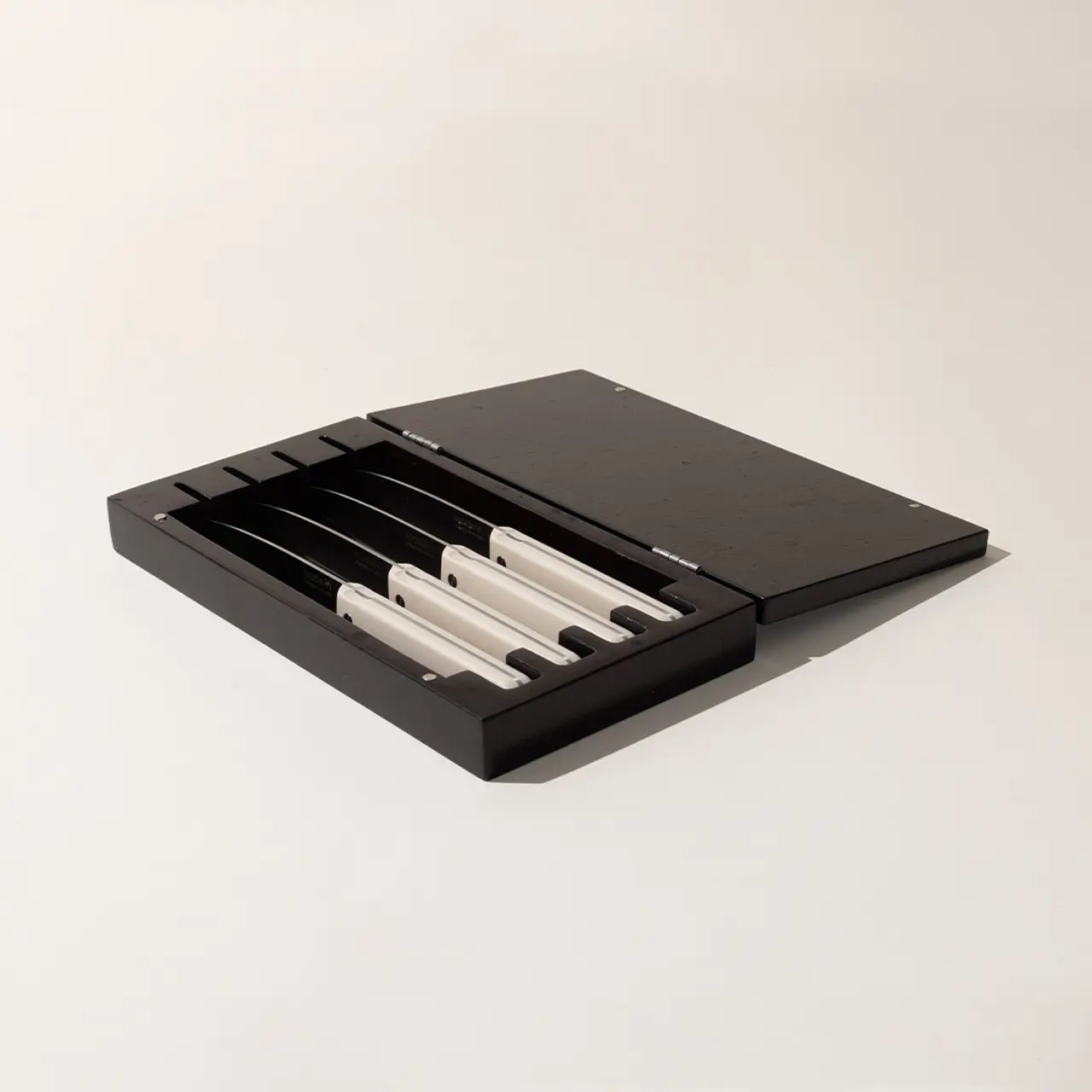 A sleek black box is open to reveal neatly arranged white minimalist design pens on a light grey background.